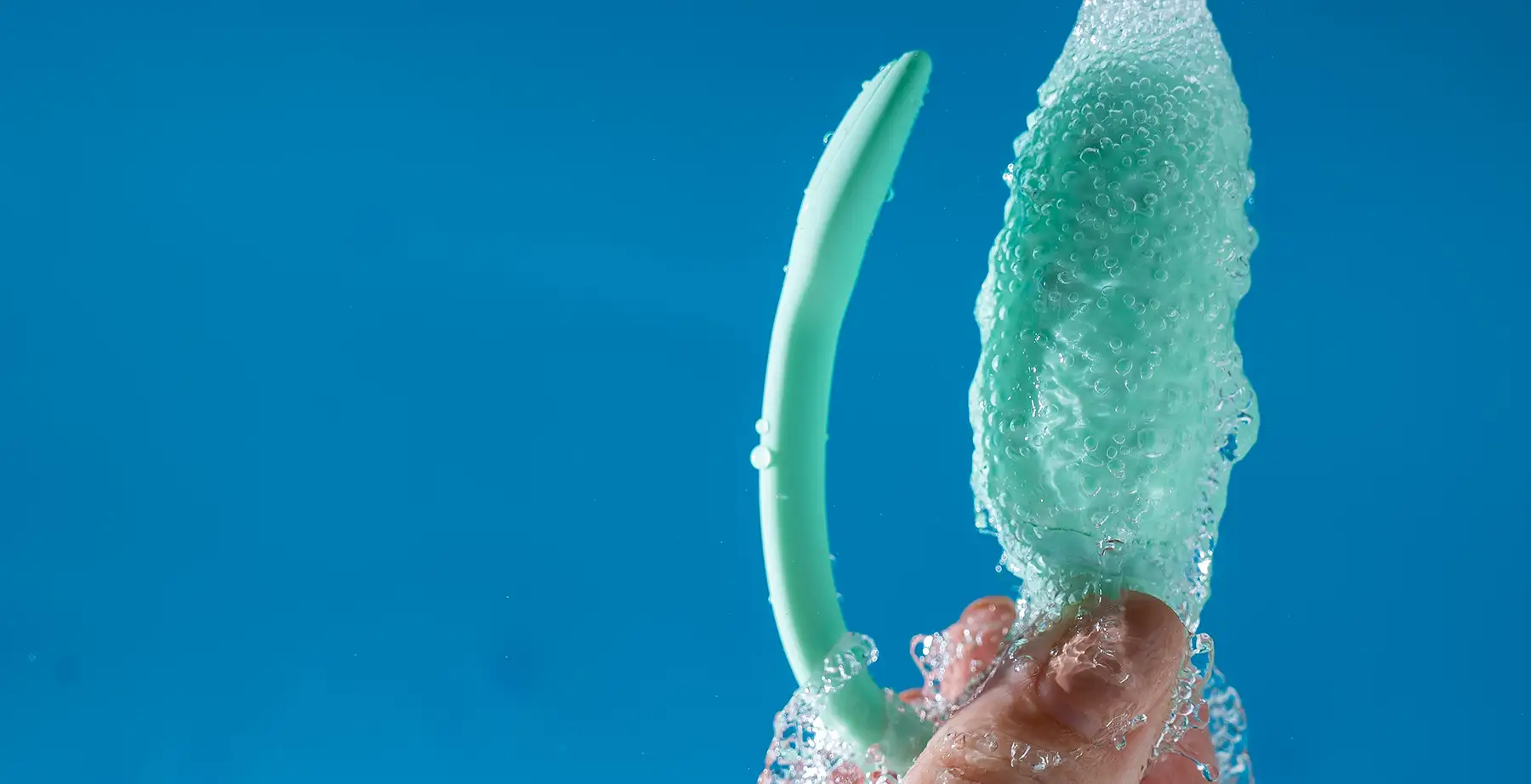 hand holding sex toy under running tap for cleaning. Safe and healthy practices for using sex toys