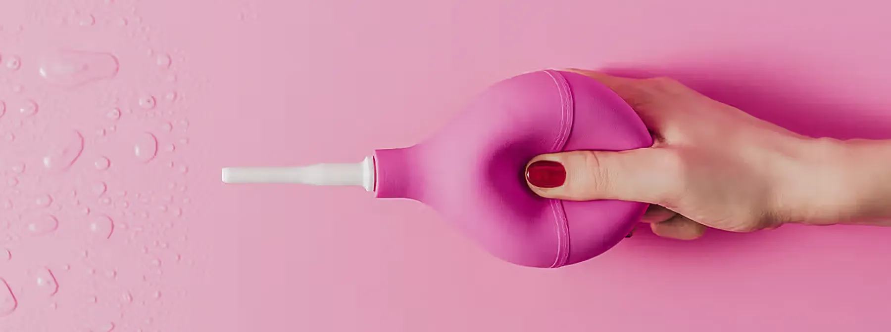 hand squeezing anal douche filled with water