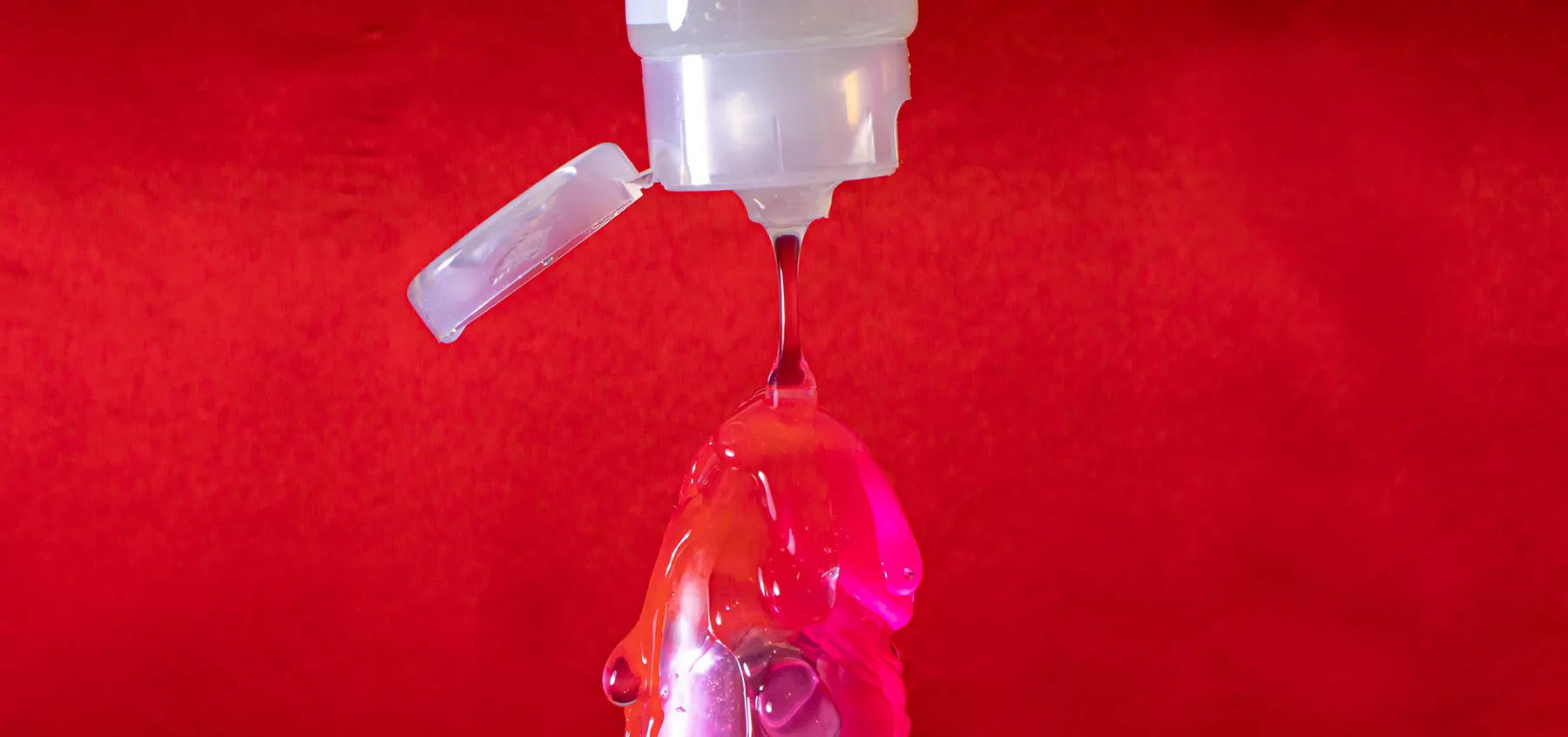 pouring lube on the tip of a dildo