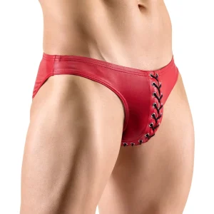 Close-up of a person modeling Svenjoyment Red Briefs with black lacing detail on the front. The image focuses on the briefs and the midsection, highlighting the muscular physique of the model.