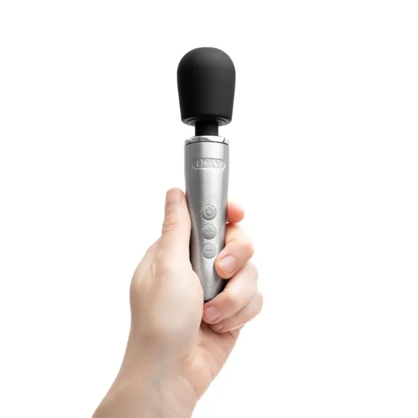 A hand holds the Doxy Go Rechargeable Travel-Friendly Wand Massager, featuring a silver and black design with a rounded head and three buttons on the handle, shown against a plain white background.