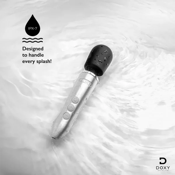 The Doxy Go Rechargeable Travel-Friendly Wand Massager with a black head and silver handle sits in swirling water, droplets on its surface. Text: "IPX-7. Designed to handle every splash!" Doxy logo appears bottom right.