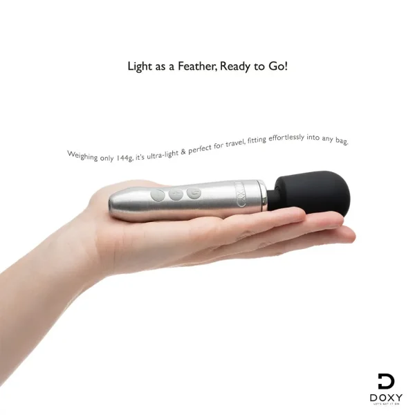 A hand holds the Doxy Go Rechargeable Travel-Friendly Wand Massager, compact, silver, and topped with a black rounded head. Text reads, "Light as a Feather, Ready to Go!" with the Doxy logo in the bottom right corner.
