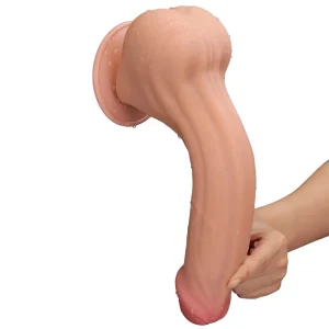 A hand holds the Sliding Skin King Sized 11.5 inch Dual Layer Dildo, showcasing its realistic, flesh-toned look, suction base, and flexible design against a plain white background. The toy appears slightly wet.