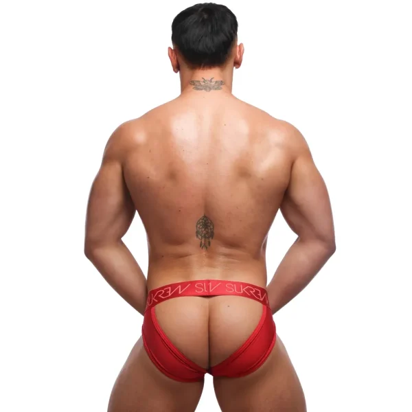 A muscular man with a back tattoo stands facing away, wearing Sukrew Liberty Red U-Style V Briefs with a branded waistband, hands on hips, against a white background.