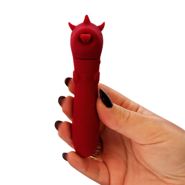 A person holds the Unihorn USB Blaze Diablo Unicorn Bullet Vibrator, a small red silicone vibrator shaped like an unicorn, featuring a power button. The vibrator is held against a white background by someone with dark nail polish.