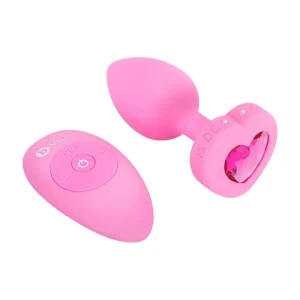 The b-Vibe Vibrating Heart Remote Controlled Butt Plug is a pink silicone plug with a heart-shaped jeweled base, shown beside its matching pink wireless remote control.
