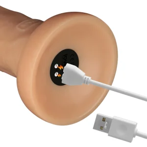 A close-up of the Power Basics 10 Inch Realistic Vibrating Dildo’s base shows it being charged with a white USB cable. The charging port is marked with lightning symbols and a CE mark.