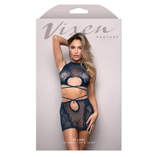 The package shows a woman in the Fantasy Lingerie Vixen At Last Tie-back Top & Skirt, a dark lace set with cutouts, posing against a light background. The packaging is labeled "Vixen Fantasy Lingerie" and "At Last Tie-Back Top & Skirt.