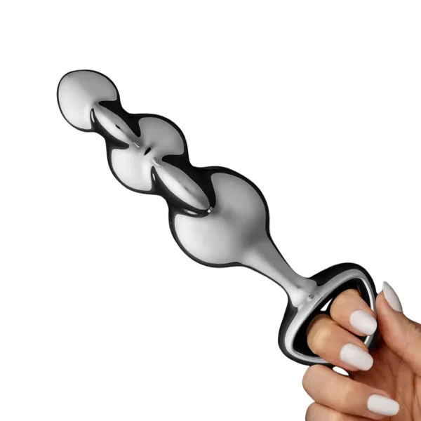 A manicured hand holds the Stainless Steel Beaded Disco Thruster Dildo, a shiny metallic toy with a flared base, against a white background.