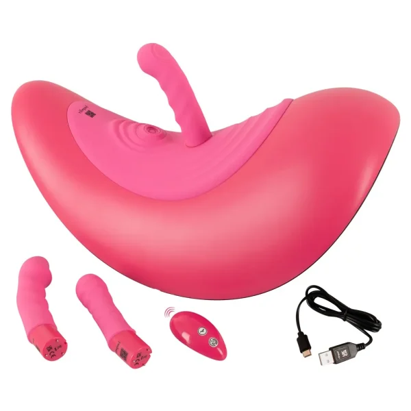The VibePad Ride On Vibrating Remote Control Saddle Vibrator is a pink, curved toy with a central insertable attachment, 3 interchangeable attachments, a remote control, and a USB charging cable shown on a white background.