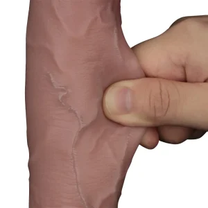 A close-up of a hand squeezing the Sliding Skin Pro II Realistic 10 Inch Dual Layer Silicone Dildo, featuring a veiny, flesh-toned texture that closely resembles human skin, set against a plain white background.
