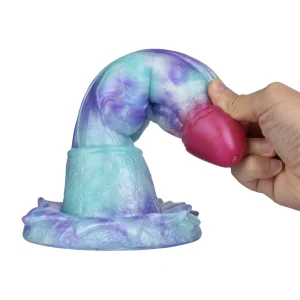 A hand bends the Tyrannosaurus 10 Inch Fantasy Dinosaur Dildo, a colourful, silicone sex toy with a textured base and a curved, marbled blue, purple, and pink shaft.