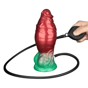 A hand squeezes a black pump attached to the Aerosx 7.5 Inch Silicone Inflatable Fantasy Dildo, a large red and green textured fantasy toy with a suction cup base.