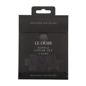 A black package labeled "Le Desir Nipple Cover Set" with a rose graphic and clear window displays cross, heart, and star-shaped nipple covers. The text says "DESIGNED FOR DESIRE." Includes 3 pairs.