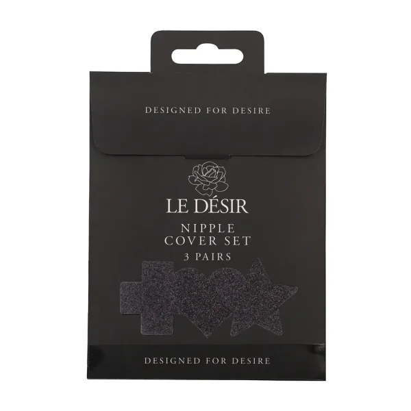 A black package labeled "Le Desir Nipple Cover Set" with a rose graphic and clear window displays cross, heart, and star-shaped nipple covers. The text says "DESIGNED FOR DESIRE." Includes 3 pairs.