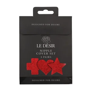 The Le Desir Nipple Cover Set comes in black packaging with "LE DÉSIR Nipple Cover Set, 3 pairs" and displaying three red glitter shapes—cross, heart, and star. The box features "DESIGNED FOR DESIRE" at the top and bottom.