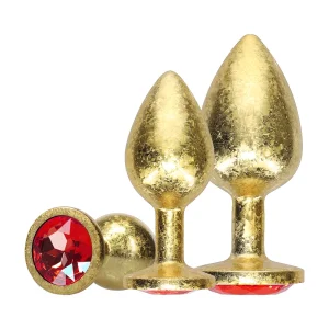 The Ouch Milan Collection Anal Plug Set features three gold coloured metal plugs in different sizes, each adorned with a red gem at the base, displayed upright against a white background.