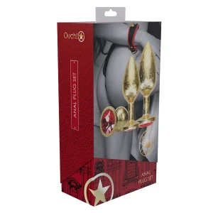 Box packaging for the "Ouch Milan Collection Anal Plug Set," featuring three gold-coloured plugs with red jewel bases. The design features a photo of a person in lingerie, product images, and a red and gold colour scheme.