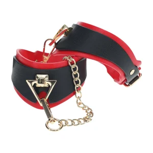 The Ouch Milan Collection Leg Cuffs feature black and red faux leather, gold-tone chain and metal hardware, a buckle closure, and triangular front detail.