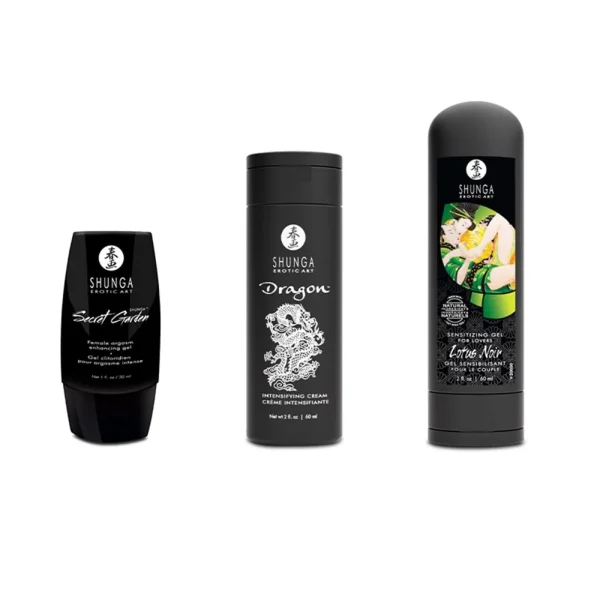 Three black bottles from the Shunga Calendar of Desires are displayed in a row, each with unique white designs and text. The third bottle features an illustrated couple in a green and yellow embrace.