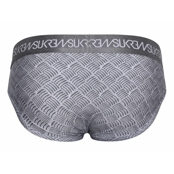 The image shows the back view of the Sukrew Checker Apex Brief: gray men's underwear with a textured metal pattern and a darker elastic waistband featuring repeated white "SUKREW" text.