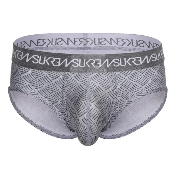 The Sukrew Checker Apex Brief is a gray men’s brief with a metal pattern and a matching waistband showcasing repeated white “SUKREW” text. The fabric is stretchy for a comfortable, form-fitting feel.