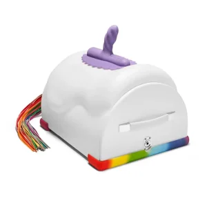 The Cowgirl Unicorn Premium Remote and App-Controlled Riding Sex Machine features a white, saddle body, a purple top handle, rainbow-coloured tail/flogger on one back, and rainbow stripes along the bottom edge.