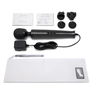 The Le Wand Diecast Plug In Vibrating Wand Massager contents, with a charger, three international plug adaptors, two instruction booklets, and a white zipped storage pouch featuring the logo, is displayed on a white background.