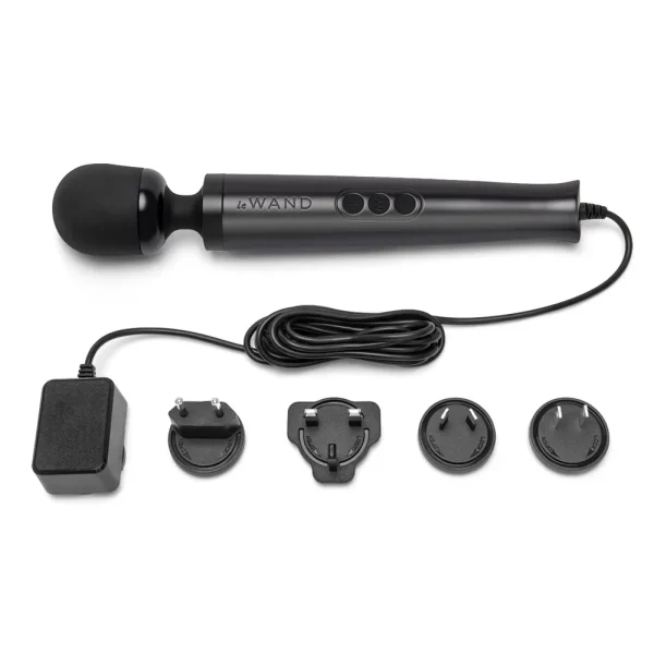 The Le Wand Diecast Plug In Vibrating Wand Massager is a black handheld massager with a rounded head, three control buttons, attached power lead, adaptor, and four international plug attachments shown below.