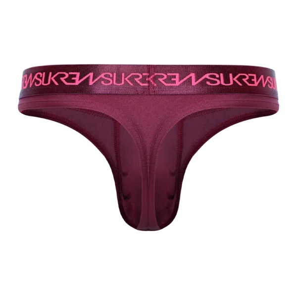 The Sukrew Clavet Classic Thong is shown from the back in claret red, featuring a wide elastic waistband with bold pink lettering. Made from smooth, sleek fabric.