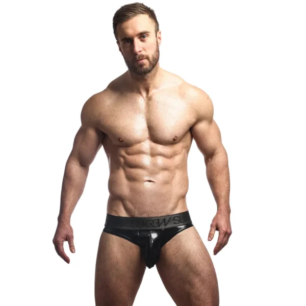 A muscular man with a beard stands against a white background, wearing only the Sukrew Fetish Black Wet Look Classic Briefs.