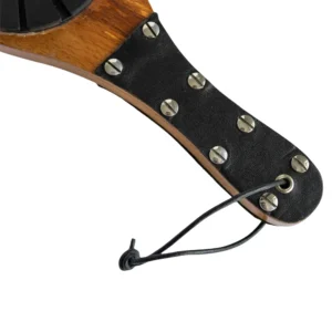 A close-up of the Wooden Boot Imprint Paddle’s wooden handle, wrapped in black faux leather with metal rivets and finished with a black cord loop at the end.