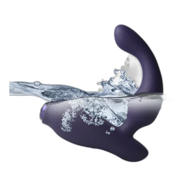 A dark purple, curved waterproof vibrator is partially submerged in water, with splashes and bubbles visible around it against a white background.