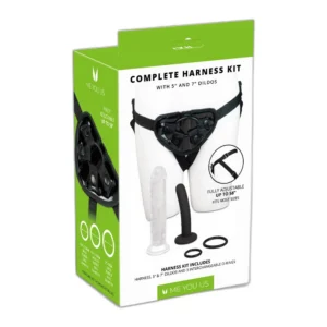 A retail box displaying a complete harness kit, including a harness, clear and black dildos, and interchangeable O-rings. The box shows a photo of the harness worn on a mannequin and lists product features.