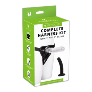 A product package labelled "Complete Harness Kit" with 5” and 7” dildos includes an image of a harness with a clear dildo attached and a black dildo beside it. The box is white and green with product information.