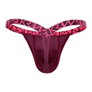A maroon thong with wide pink elastic waistband featuring bold black "SUKREW" lettering. The waistband forms a V-shape above the hips, and the fabric has a smooth, fitted design.