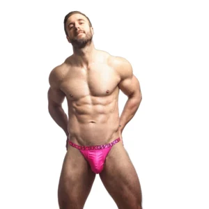A muscular man with a beard poses confidently in bright pink pants, standing against a plain white background with his hands behind his back.
