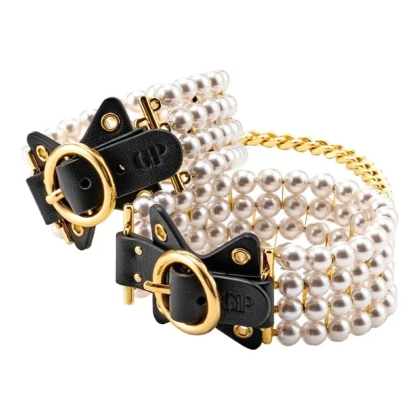 ballroom-pearl-ankle-cuffs-5 A set of three bracelets, each featuring multiple strands of white pearls with black leather accents and gold-coloured metal buckles, alongside a gold chain bracelet.