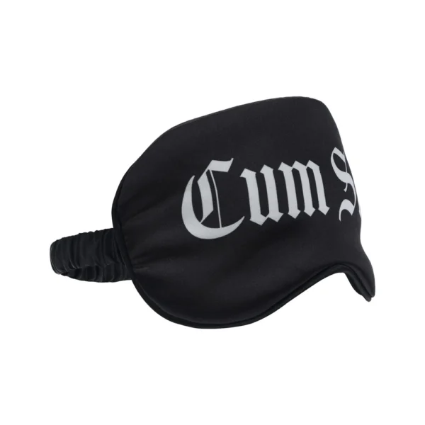 A black sleep mask with the word “Cum” in large white Gothic-style lettering across the front.