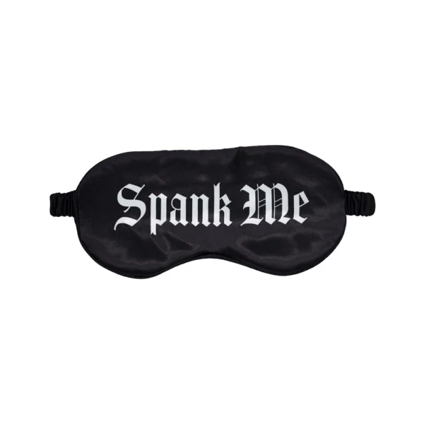 A black satin eye mask with the words "Spank Me" printed in bold, white Gothic-style letters across the front.