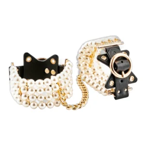 A pair of black leather cuffs decorated with rows of white beads, connected by a gold chain. The cuffs feature gold fittings and star-shaped accents.