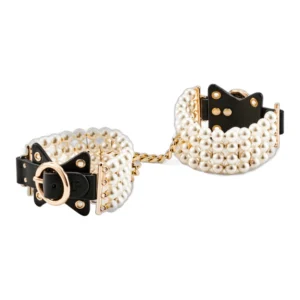 A pair of elegant handcuffs made of black leather and adorned with multiple strands of pearls, connected by a gold chain.