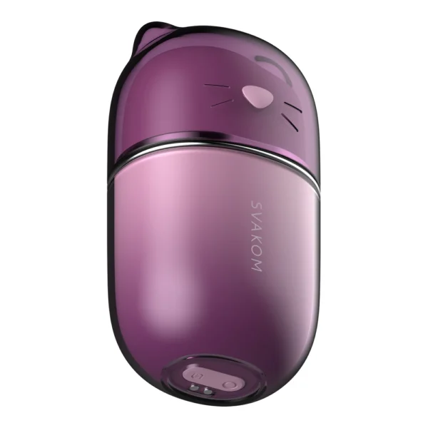 A small, oval-shaped purple device with a glossy finish, featuring cat-like ears and whiskers on the top portion. The word "SVAKOM" is printed vertically on the lower half.