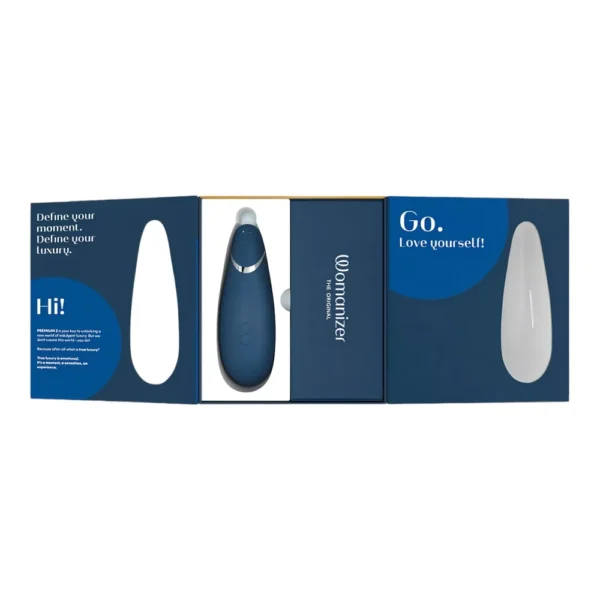A blue Womanizer Go device in its open packaging, with encouraging messages printed inside, including “Go. Love yourself!” and “Define your moment. Define your luxury.”.