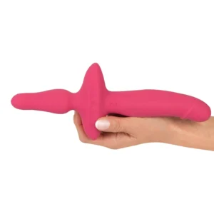 A hand holding a bright pink, dual-ended silicone adult toy with a curved, ergonomic shape and a central handle.