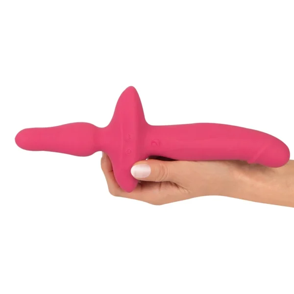 A hand holding a bright pink, dual-ended silicone adult toy with a curved, ergonomic shape and a central handle.