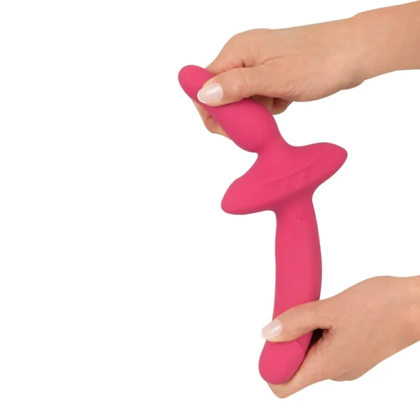 Two hands hold and bend a pink, flexible silicone toy with two different-sized ends and a wide middle section, against a white background.