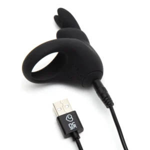 A black silicone ring-shaped vibrator with bunny ear extensions is shown charging via a USB cable.