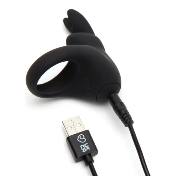 A black silicone ring-shaped vibrator with bunny ear extensions is shown charging via a USB cable.